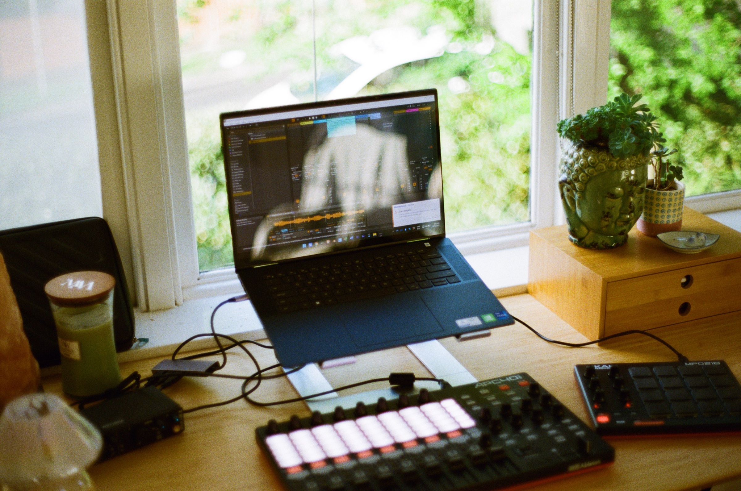 Desk setup with laptop, music controller, and plants